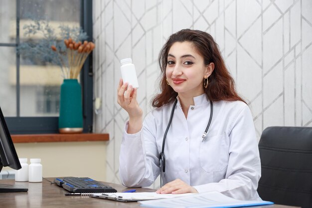 Портрет молодой работницы здравоохранения, держащей капсулу с наркотиками и смотрящей в камеру Высококачественное фото