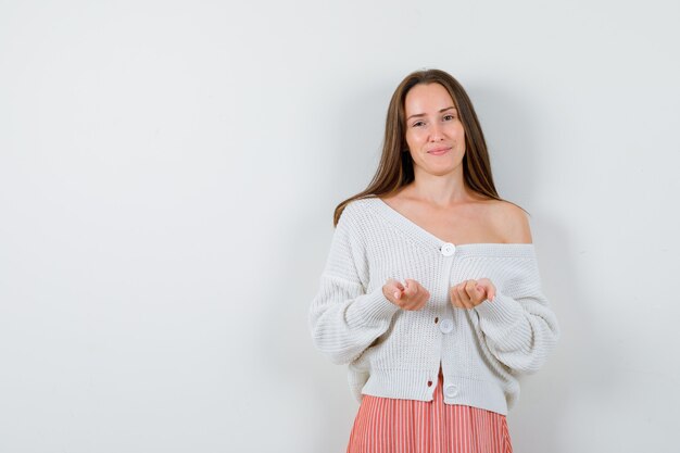 Portrait of young female keeping hands closed in cardigan isolated