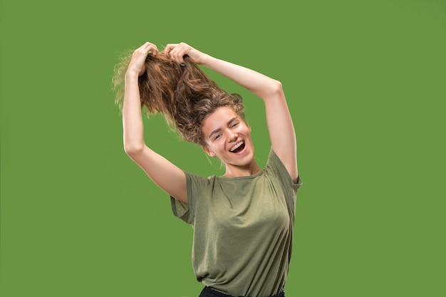 Portrait of young female model dancing isolated on green wall