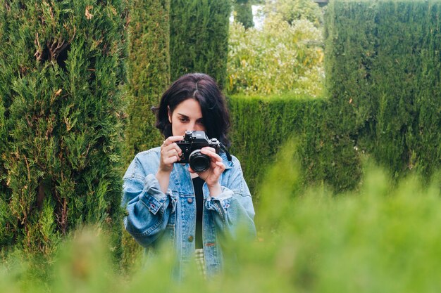 Портрет молодого женского фотографа фотографируя природа с камерой