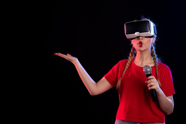 Portrait of young female playing vr and singing with mic dark  visual music games