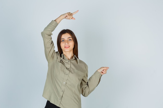 Portrait of young female pointing right in shirt, skirt and looking merry front view