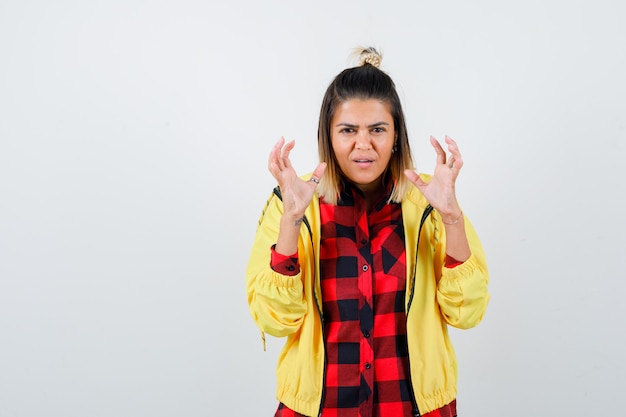 Free photo portrait of young female showing claws imitating cat in checkered shirt, jacket  and looking playful front view