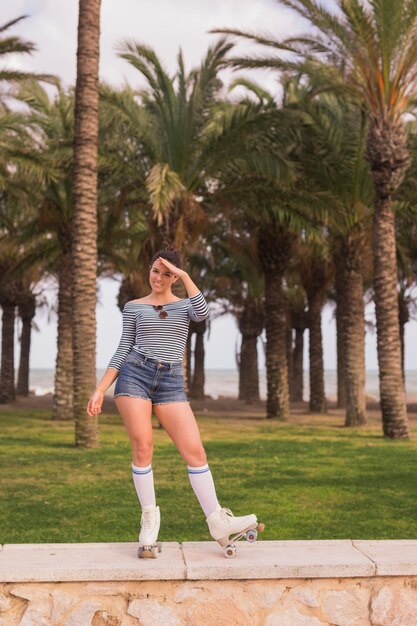 Portrait of a young female skater eye shielding standing in front of trees