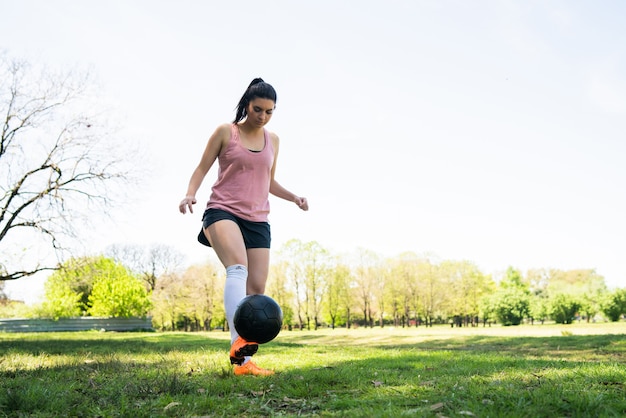 Портрет молодой женщины-футболиста, бегающей вокруг конусов во время тренировки с мячом на поле