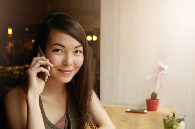 Ritratto di giovane donna con capelli castani utilizzando il telefono