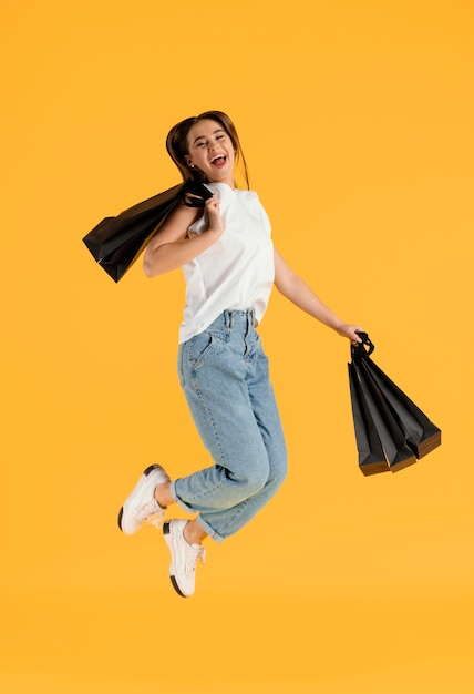 Portrait young female with shopping bags jumping