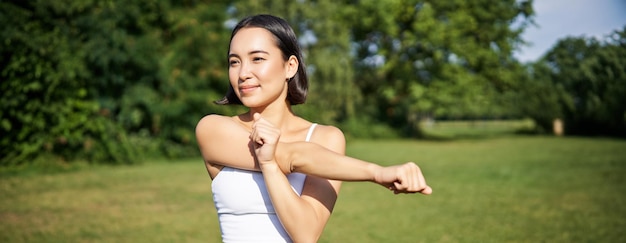 Free photo portrait of young fitness woman stretching her arms warmup before training session sport event in