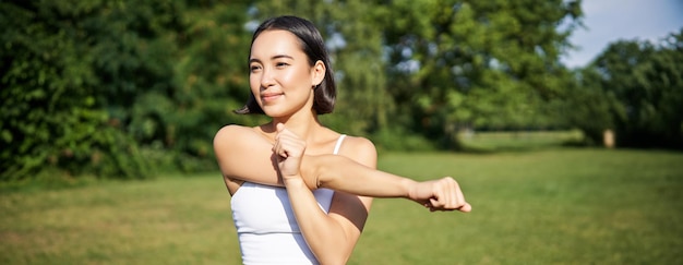 Portrait of young fitness woman stretching her arms warmup before training session sport event in