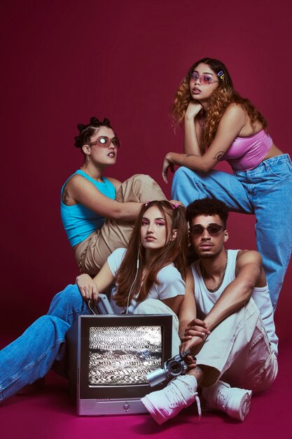 Portrait of young friends in 2000s fashion style posing with tv