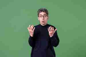 Free photo portrait of young genius man dressed casually in studio shot on green wall