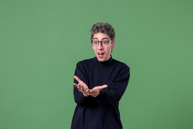 Free photo portrait of young genius man dressed casually in studio shot happy on green wall