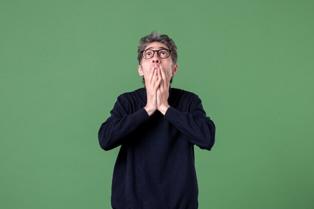 Portrait of young genius man dressed casually in studio shot looking above on green wall