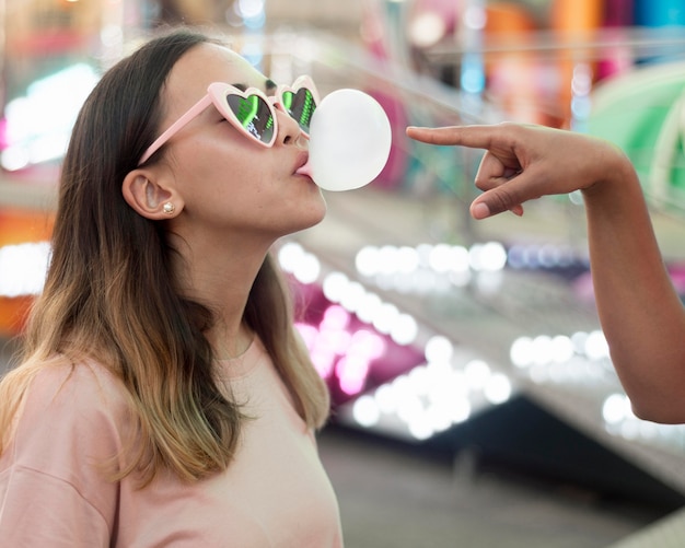 Free photo portrait of young girl blowing bubble gum