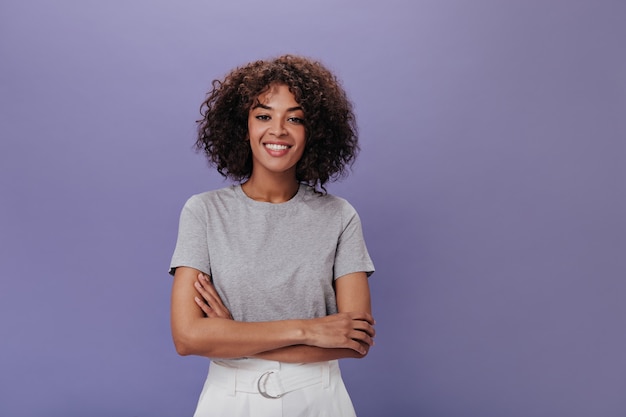 Portrait of young girl in gray t-shirt on purple wall