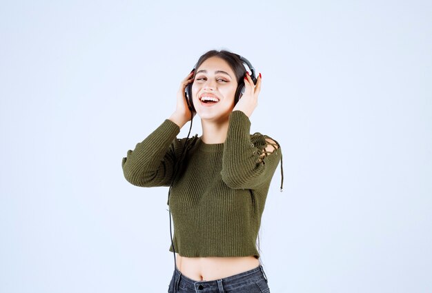 Portrait of young girl in headphones listening to music and giving ok sign.