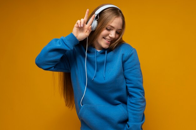 Portrait of a young girl listening to music and showing the peace sign