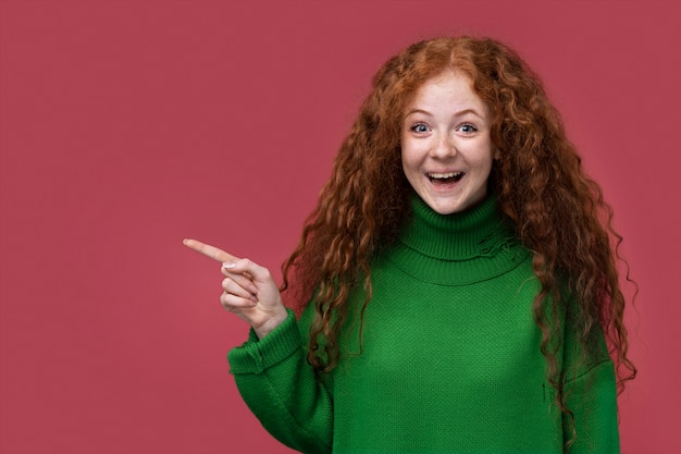 Free photo portrait of young girl looking happy and pointing to the right