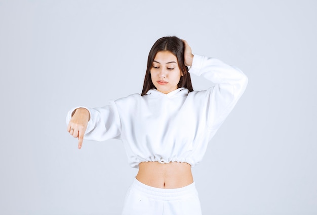 Portrait of young girl model pointing down.