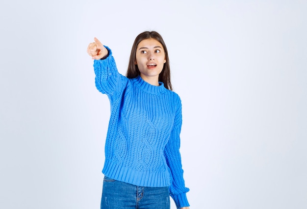 Portrait of a young girl model standing with crossed hands and looking away.