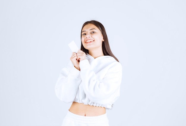 Portrait of a young girl model with a card on white-gray background.