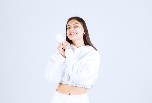 Portrait of a young girl model with a card on white-gray background.