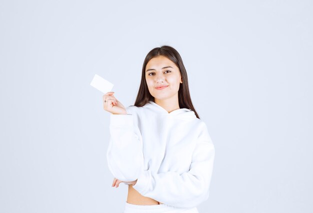 Portrait of a young girl model with a card on white-gray background.