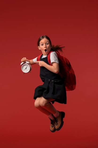 Portrait of young girl student in school uniform jumping mid-air