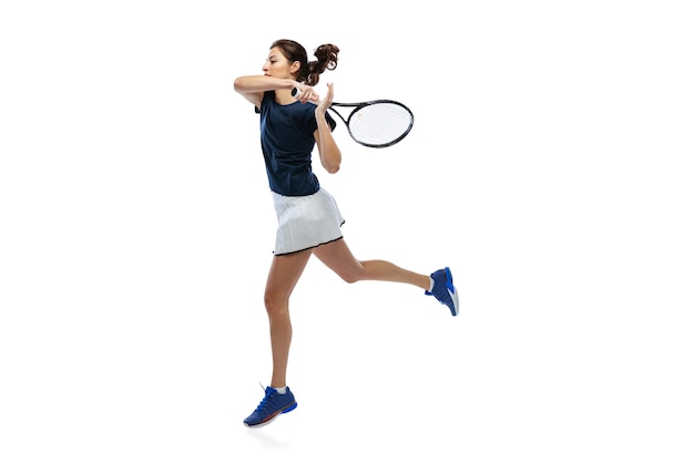 Portrait of young girl tennis player in uniform training isolated over white studio background