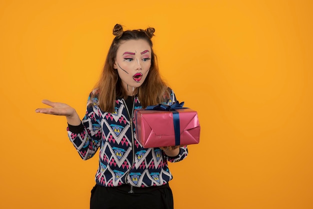 Portrait of young girl wearing creative makeup and looking at her gift box. High quality photo