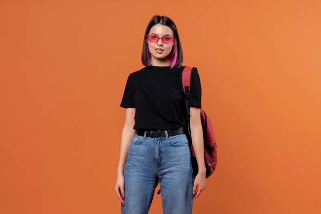 Portrait of a young girl wearing sunglasses and holding her backpack