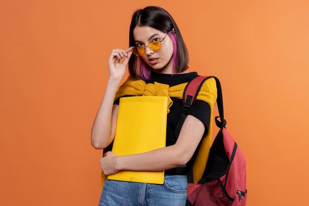 Free photo portrait of a young girl wearing sunglasses and holding her folder