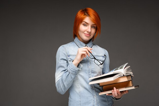 Portrait of young girl with books over grey background. Copy spa
