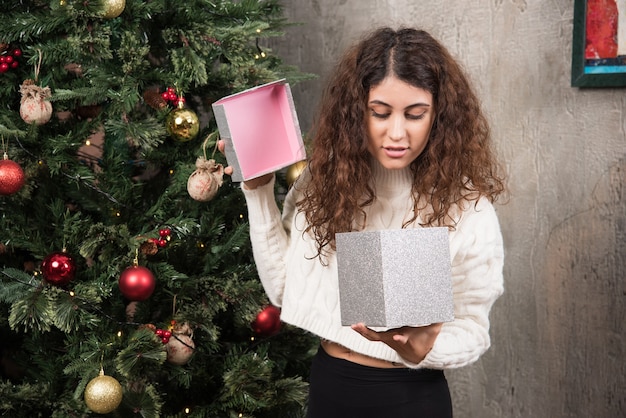 Portrait of young girl with curly hair opening a box with gift 