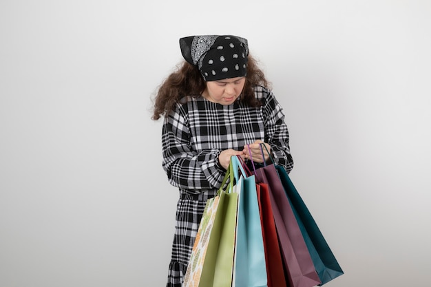 Free photo portrait of young girl with down syndrome looking at bunch of shopping bag.