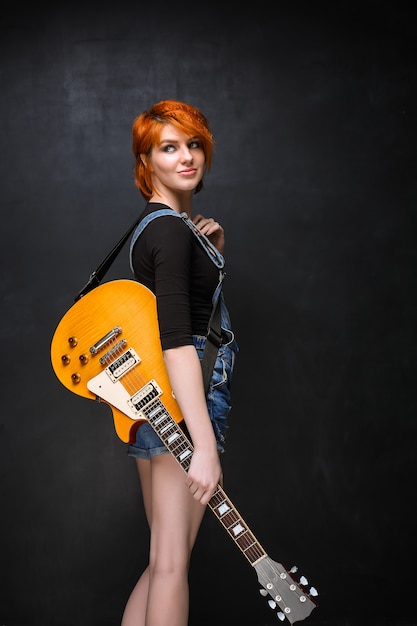 Free photo portrait of young girl with guitar over black background.