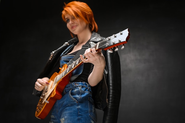 Foto gratuita ritratto di giovane ragazza con la chitarra su sfondo nero.