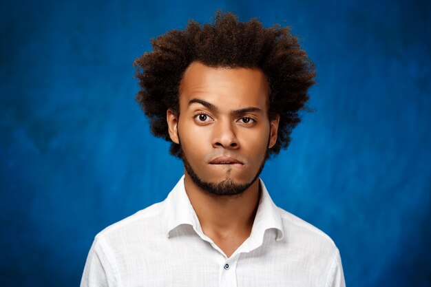 Портрет молодого красивого африканского человека над голубой стеной.