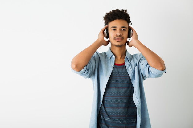 Portrait of young handsome black man listening to music on headphones on white