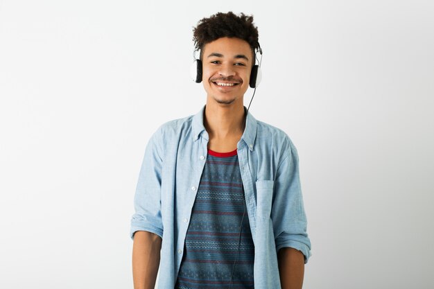 Portrait of young handsome black man listening to music on headphones on white