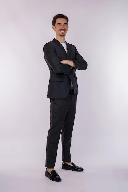 Portrait of young handsome businessman wearing suit standing with crossed arms with isolated on studio white background