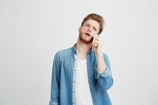 Portrait of young handsome guy with beard speaking on phone.