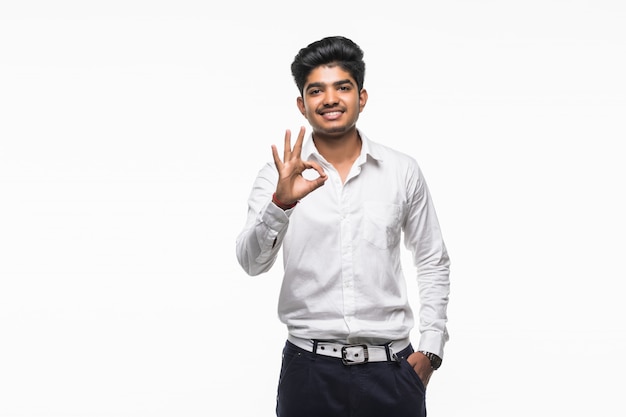 Portrait of young handsome happy, smiling excited man giving OK sign with fingers, isolated on white wall
