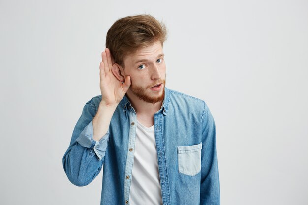 Portrait of young handsome man eavesdroping looking at camera.