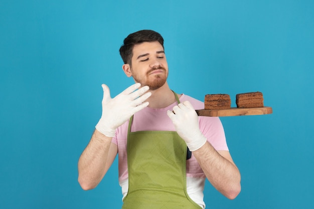 Portrait of young handsome man holding fresh homemade cake slices .