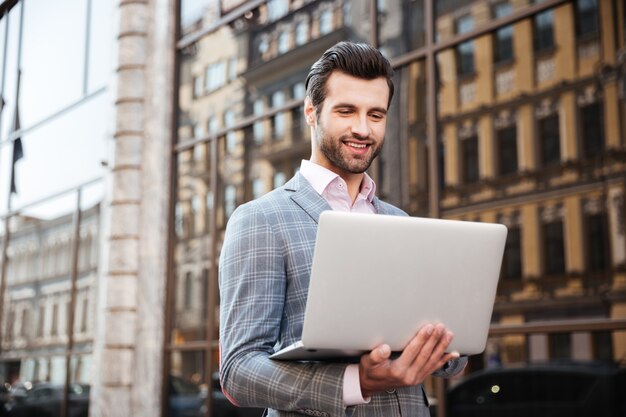 Portrait of a young handsome man in jacket holding laptop