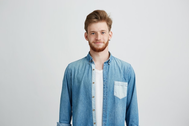 Portrait of young handsome man in jean shirt smiling looking at camera.