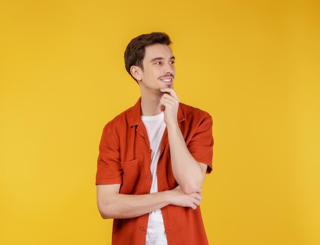 Portrait of young handsome man looking confident at the camera with smile with crossed arms and hand raised on chin over isolated background