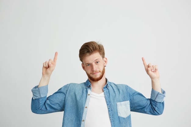 Free photo portrait of young handsome man pointing finger up.