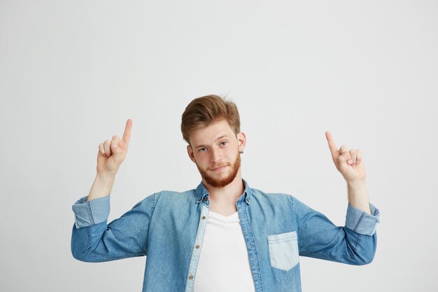 Portrait of young handsome man pointing finger up.